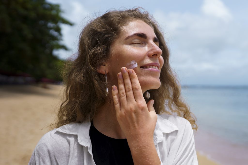 Woman Applying Sunscreen on Her Cheek at a Beach in the UAE